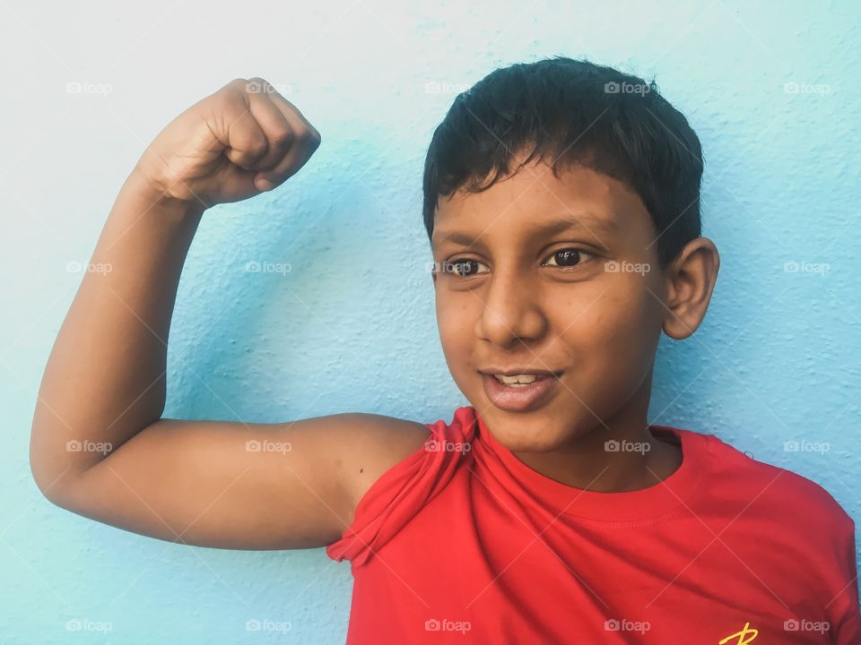 Indian kid flexing his muscle and showing his strength 