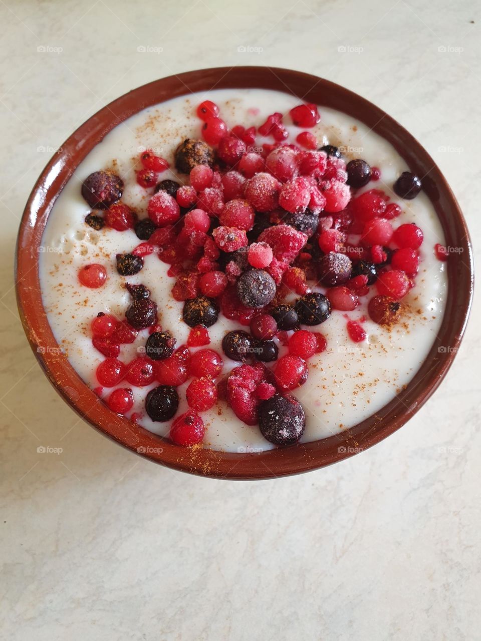 Delicious morning oatmeal porridge with berries, banana, cinnamon and honey.