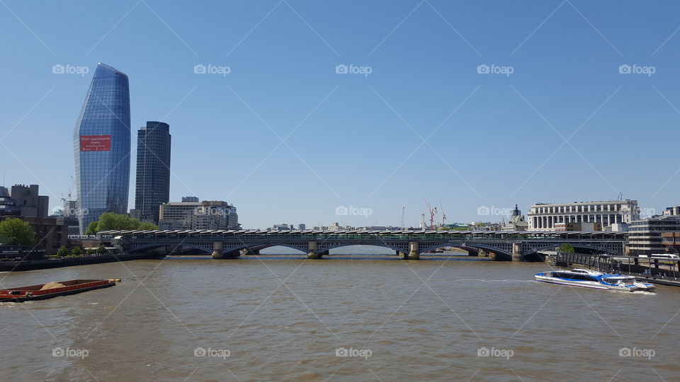 View of Blackfriars Bridge and the River Thames, central London, UK, with river traffic and blue skies.