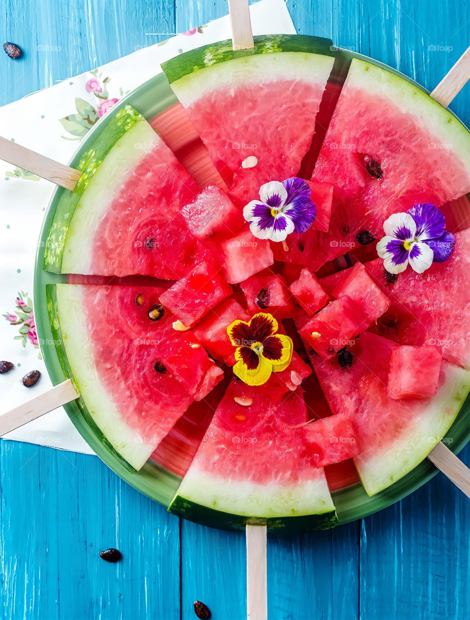 Overhead view of watermelon sticks on a plate on blue wooden surface.