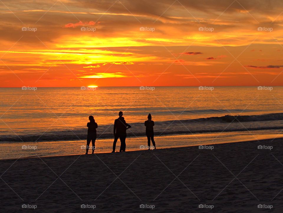 Sunset reflection - A family watches the sunset mark the end of the day, but the beauty lies in the promise of a new dawn