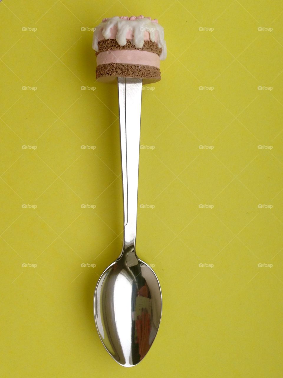 spoon with cupcake on top on yellow back