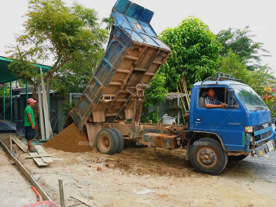 Working.. Trucks carrying sand pouring sand into the construction area.