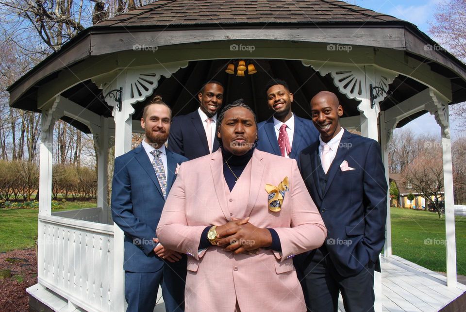 A handsome groom and his groomsmen, smiling into the camera on a gorgeous blue day