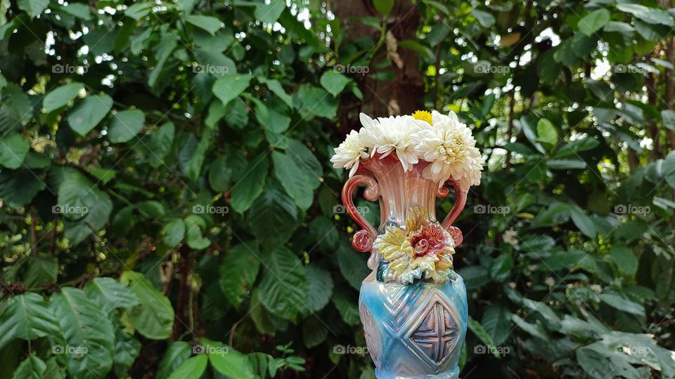 Beautiful white flowers in a colourful flowerpot with a flower sculpture, Flowers in a vase, colourful vase, white flowers in a vase