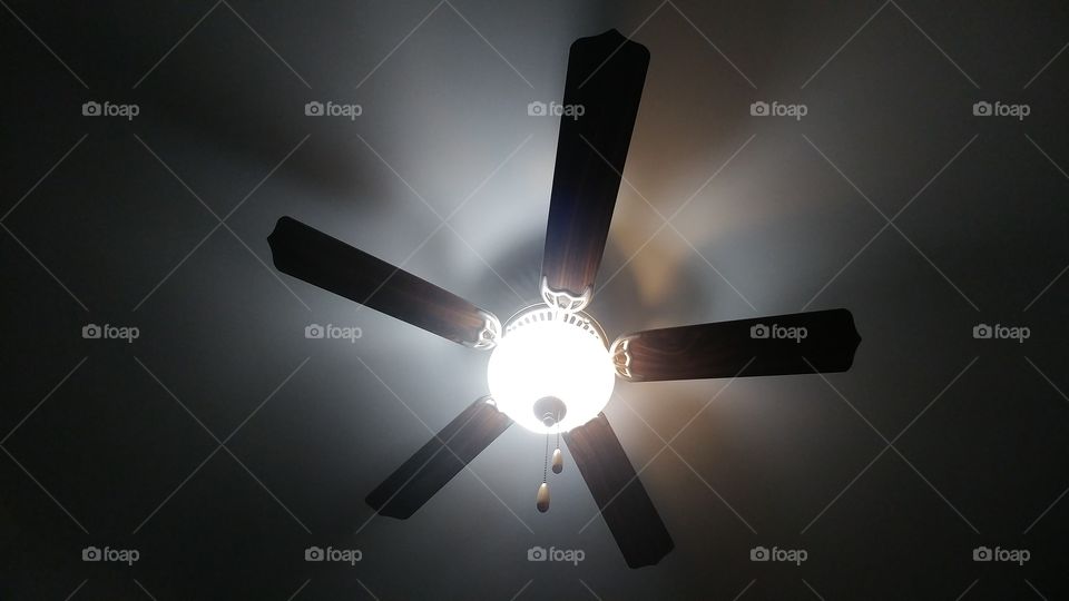 fan with light on against white ceiling