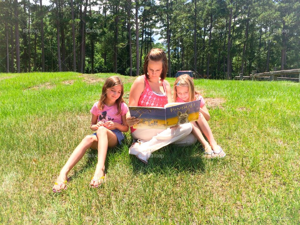 Mother and daughters reading a book in forest