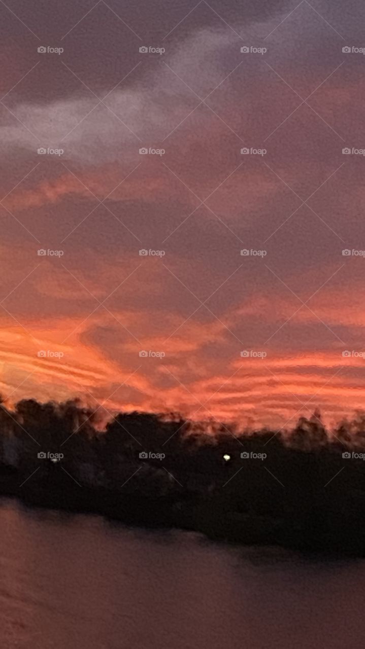 Sundown Completed Sky is opening up. Blistering Orange Slivers along with Yellows upper atmosphere bleeding down to the lower with Grays Blues Violets tops of high clouds getting into the act by opening up.