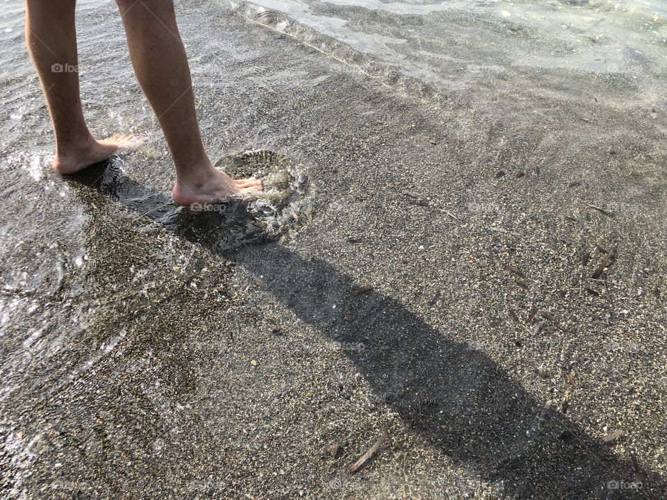 Legs on water’edge beach