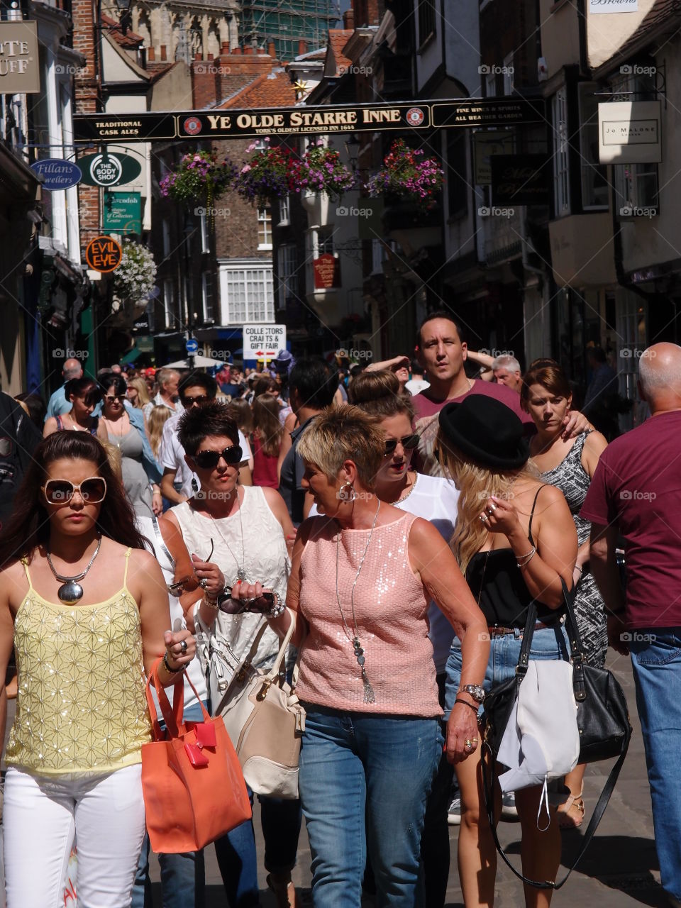 Crowds of people walking through shopping districts in An English town on a sunny summer day. 