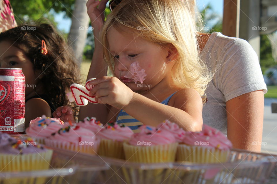 little girl eating cupcakes at her second birthday party