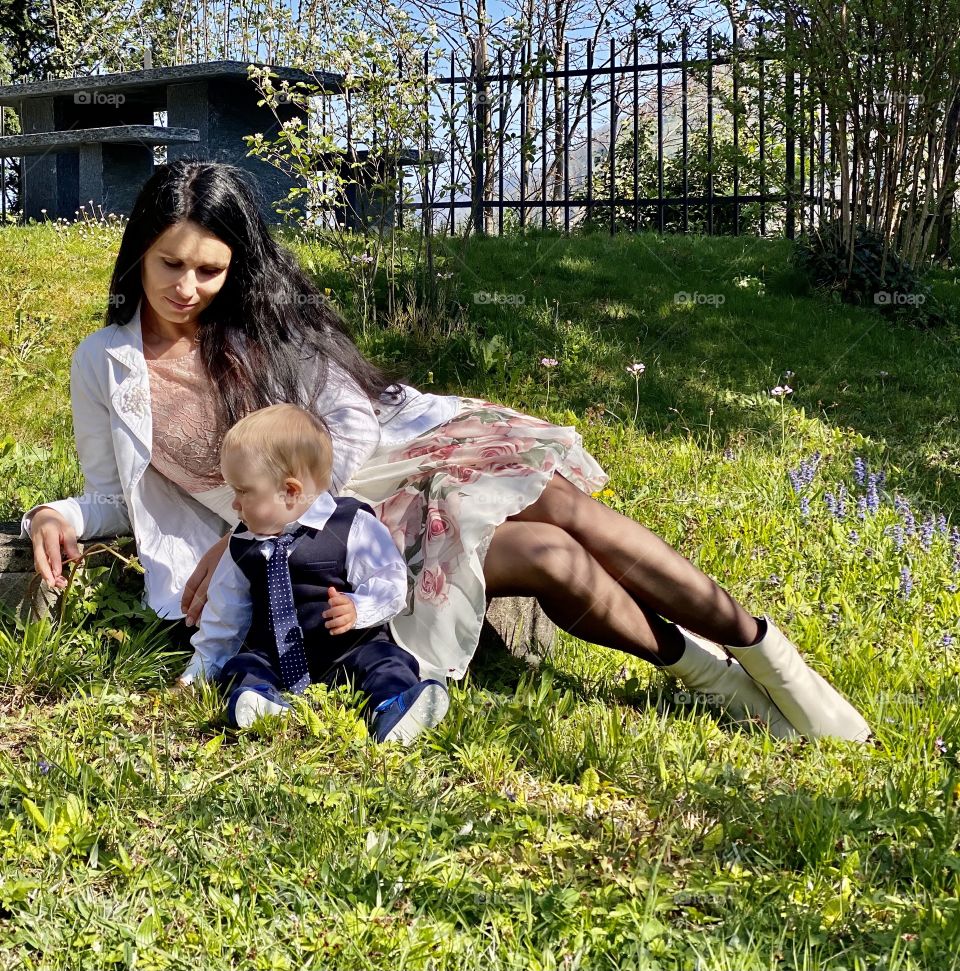 a young mother with a small child are sitting on a green lawn