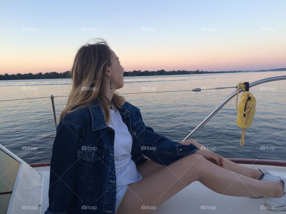 Cute girl on a boat in front of a beautiful sunset