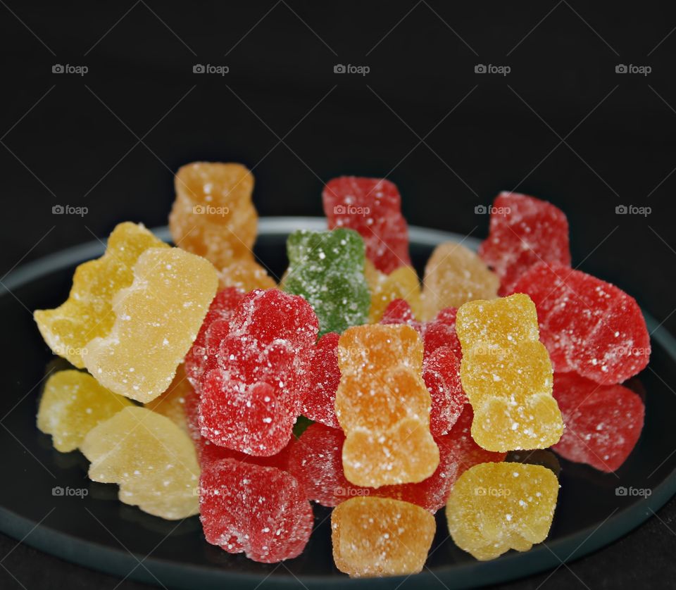 colorful sugar coated gummy bears sitting on a glass mirror