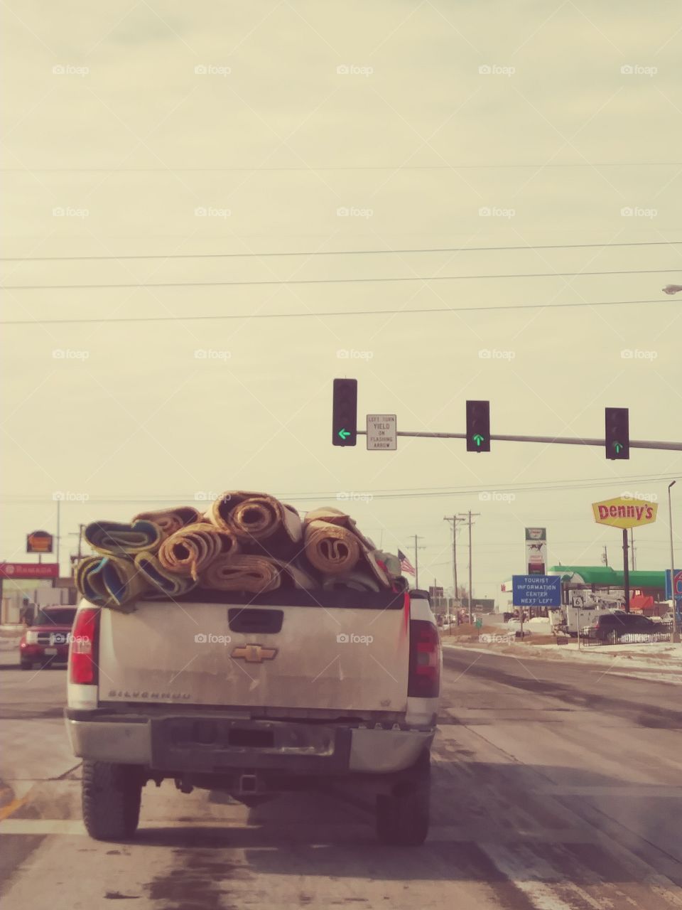 traveling through NOrth West and see this pick-up truck filled over the top of bed with rolls and rolls of carpet. white truck is coming up on a green light.