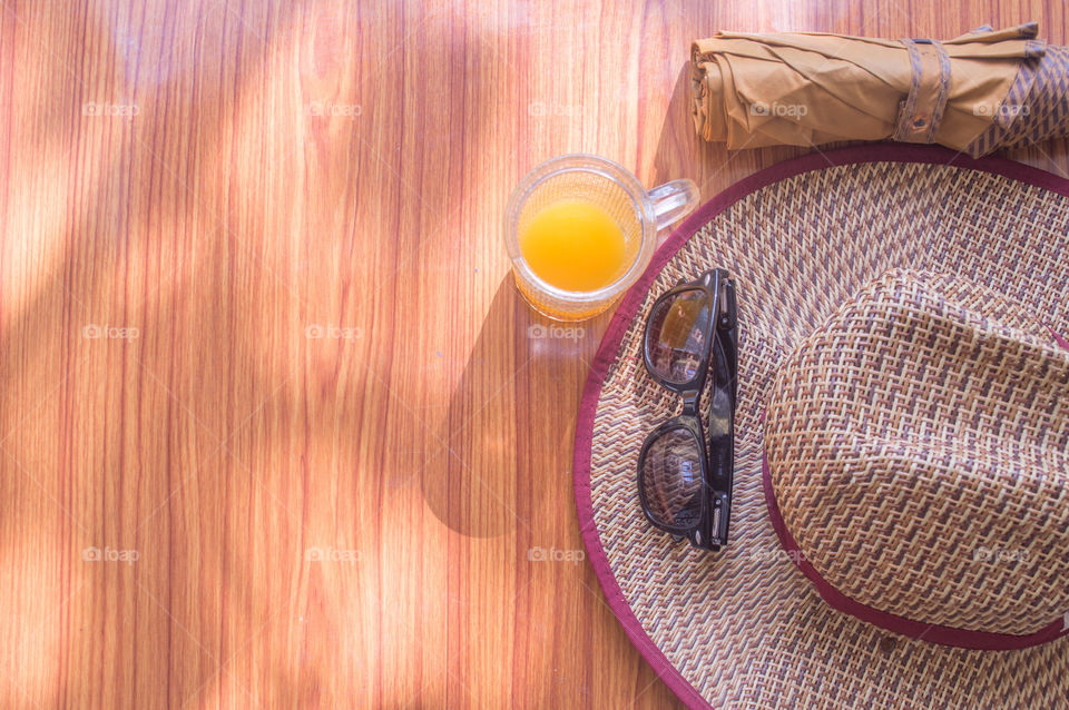 Ready to travel. Top view beach background of essential modern summer women travel accessories in a wooden table. Sunglasses, umbrella, Straw hat and a glass of juice. Holiday theme with room for text