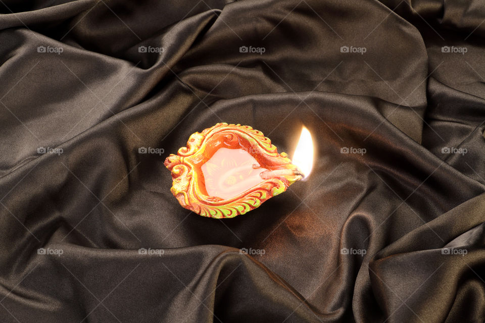 Indian festival Diwali diya oil lamp on black satin background