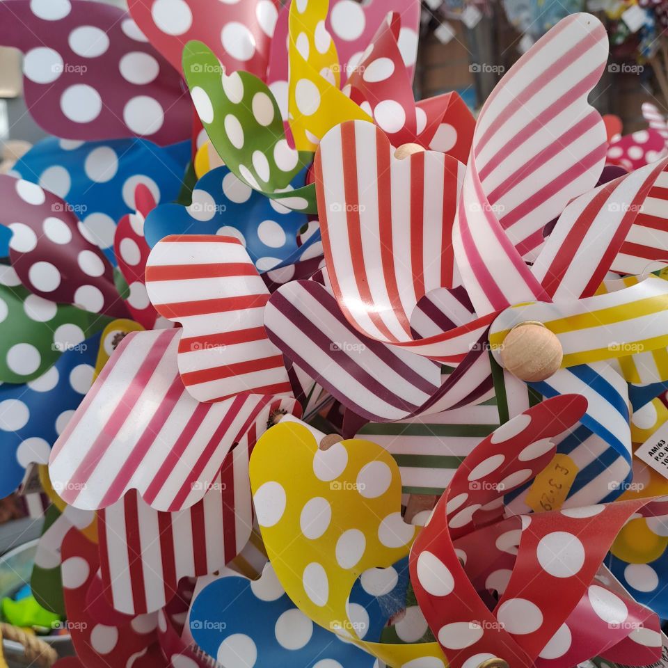 brightly coloured sriped and spotted childrens windmill toys clustered together