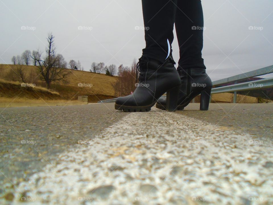 Women's black boots in the middle of the road