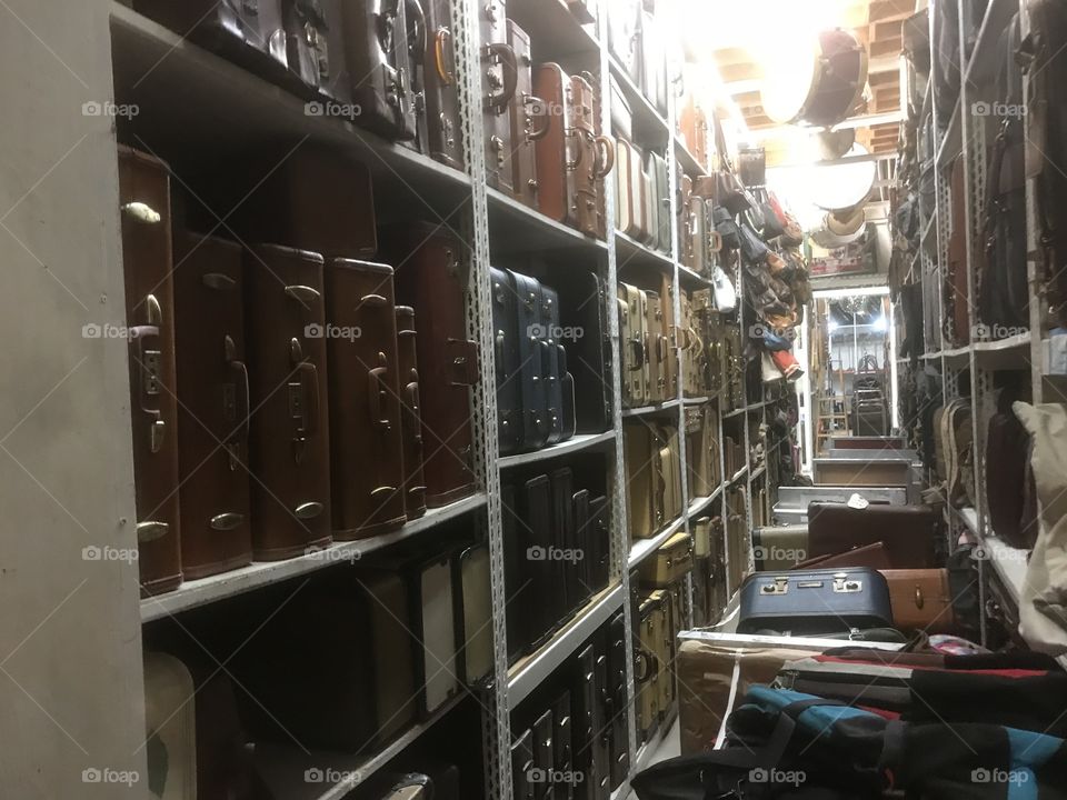 Floor to ceiling shelves holding a collection of luggage and briefcases 