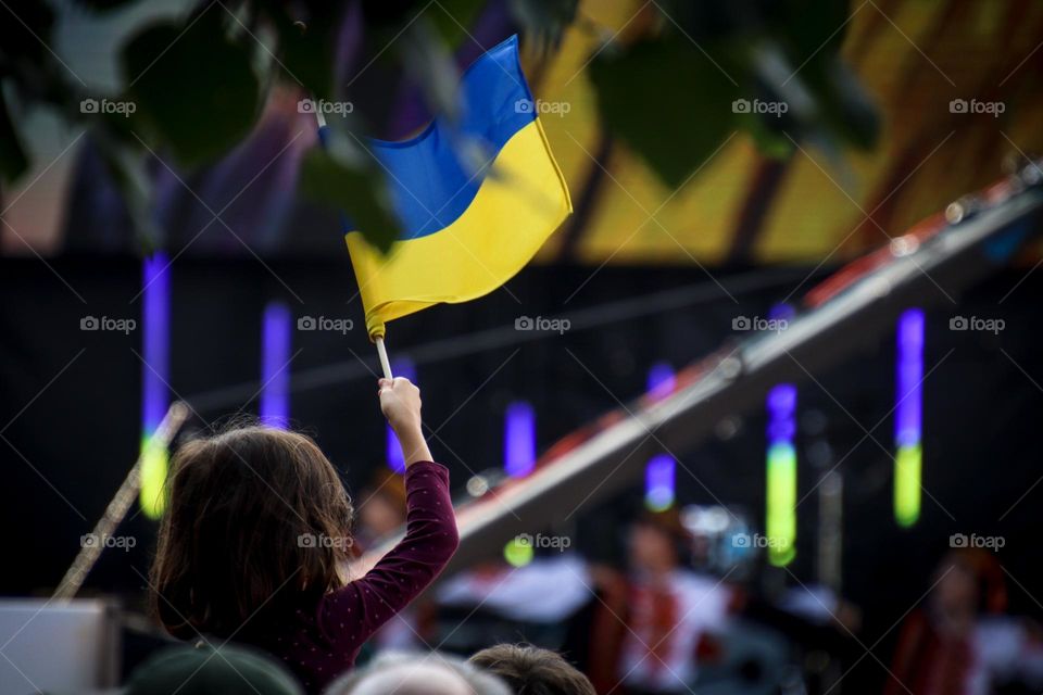 Girl is holding Ukrainian flag over the heads of people in the crowd