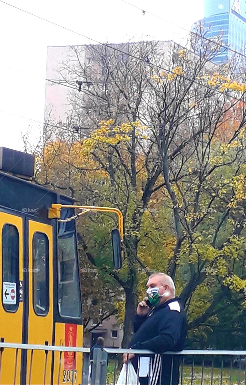 city trafic - yellow tramway autumn  coloured trees a man in the mask