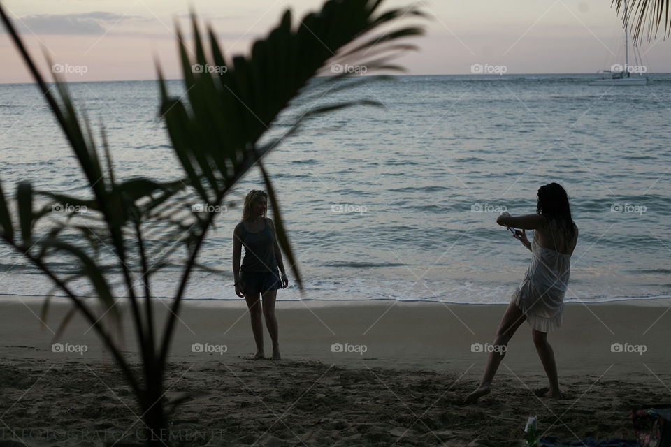 girls taking photos on the beach on the evening. girl on the beach, photographs her girlfriend in the Sunset