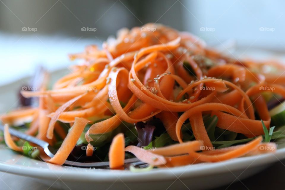 Thin carrot slices on top of a salad 