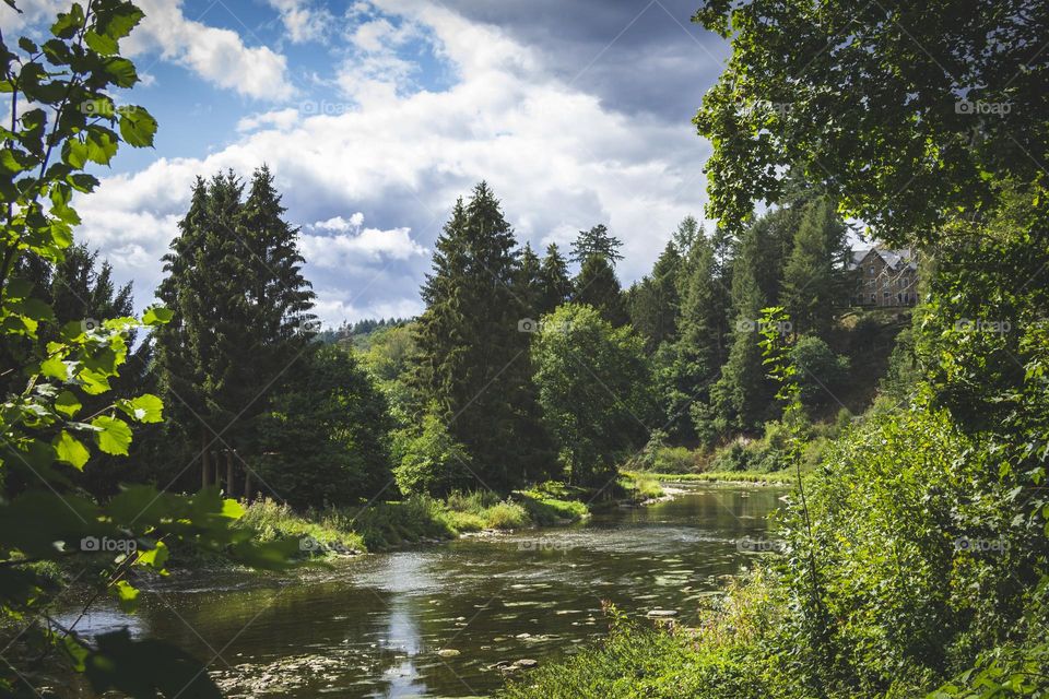 A landscape photo of the semois river in the belgian ardennes. the river is surrounded by forest and hills.