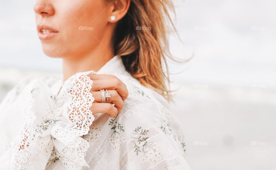 Young woman with beautiful jewellery rings on hands on sea background 