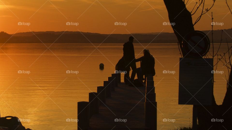Silhouette of two people at pier during sunset