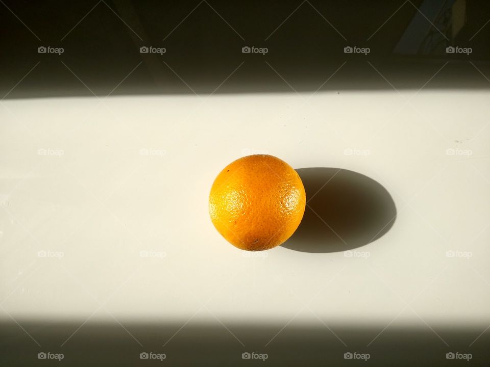 Апельсин и тень. Фрукт висит в воздухе.
Orange and shadow. The fruit hangs in the air.
