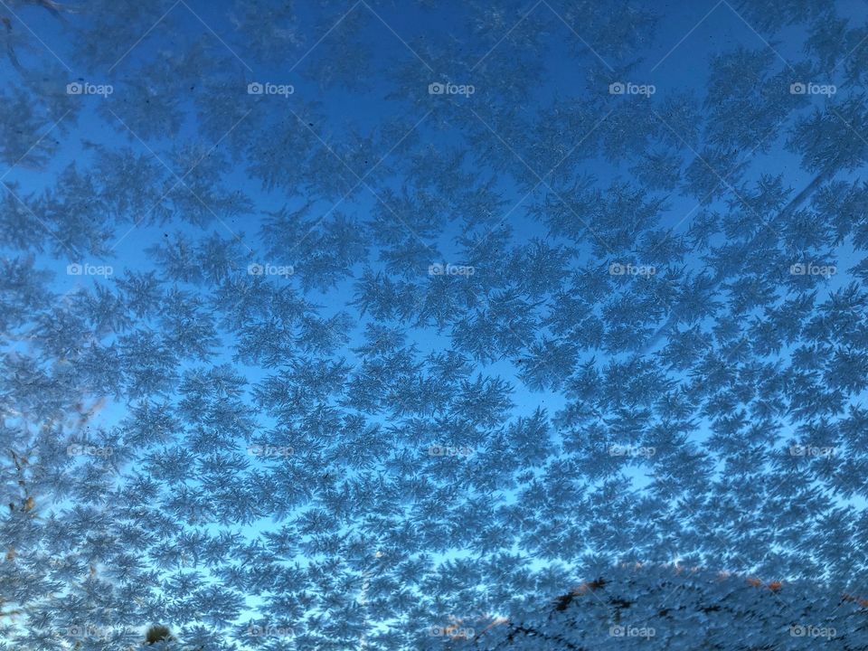 Ice crystals on the windscreen in a winter morning with a blue sky 