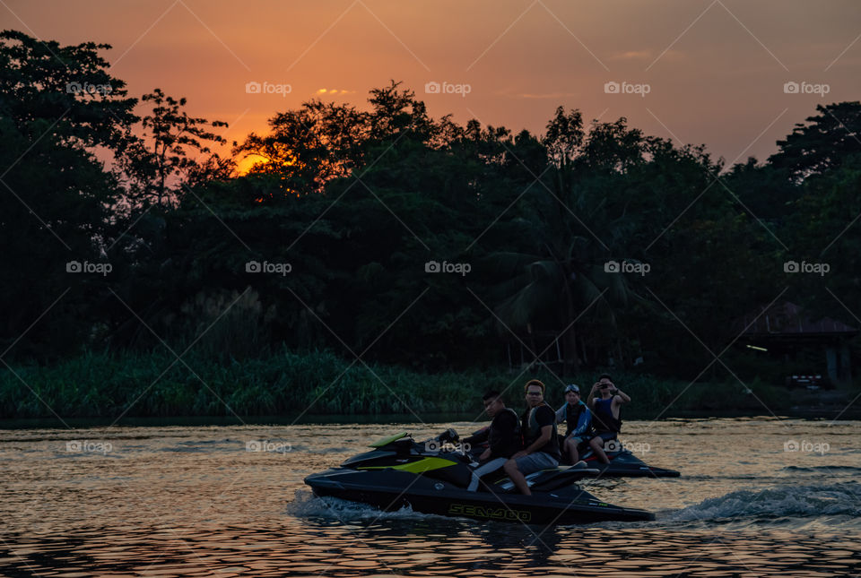 Tourists drive the Jet Ski and the sunset light in Khwae Noi river at Kanchanaburi Thailand .December 2, 2018