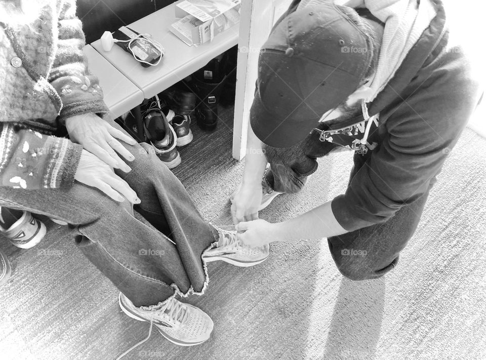 Black-and-white of sun helping mom put shoes on