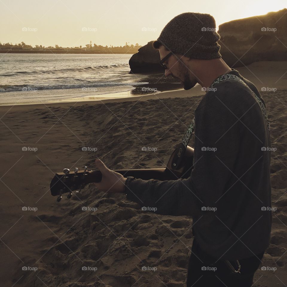 Young man playing guitar at beach