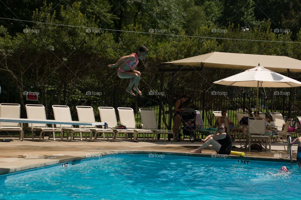 Little girl jumping of the board into the pool