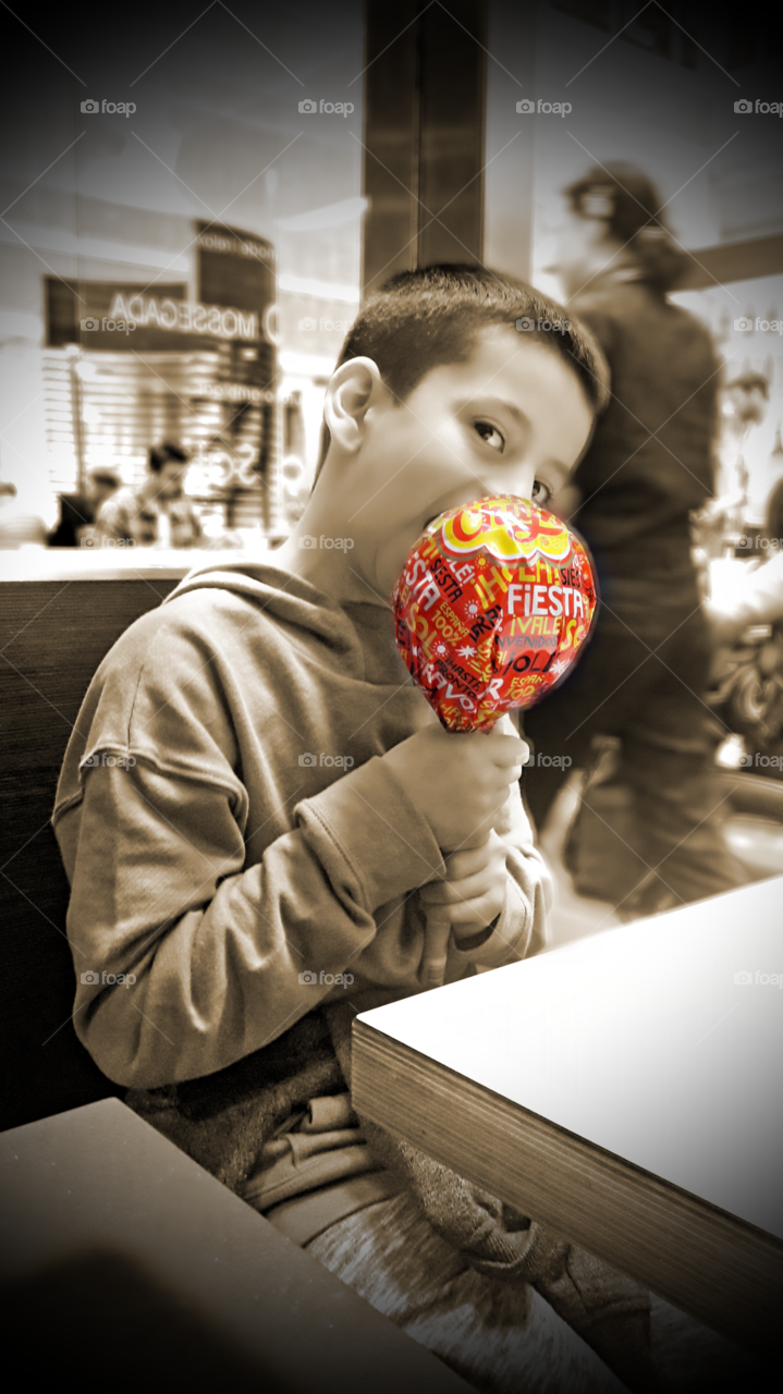 Boy sitting in restaurant holding object in hand