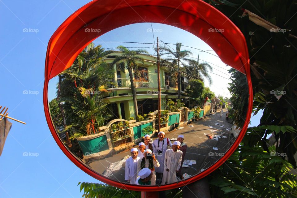 Mirror to see the road from two directions, the background of the house and a group of men in white robes.