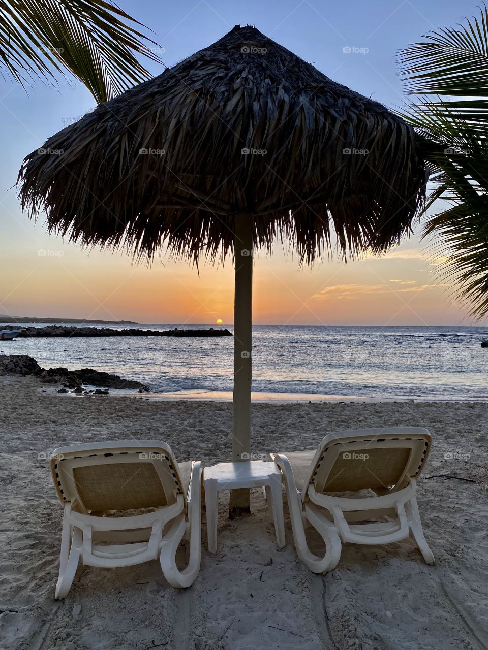 Beautiful sunset by a beach in the Bahia Principe Grand Jamaica hotel area with chaise lounges in front of it