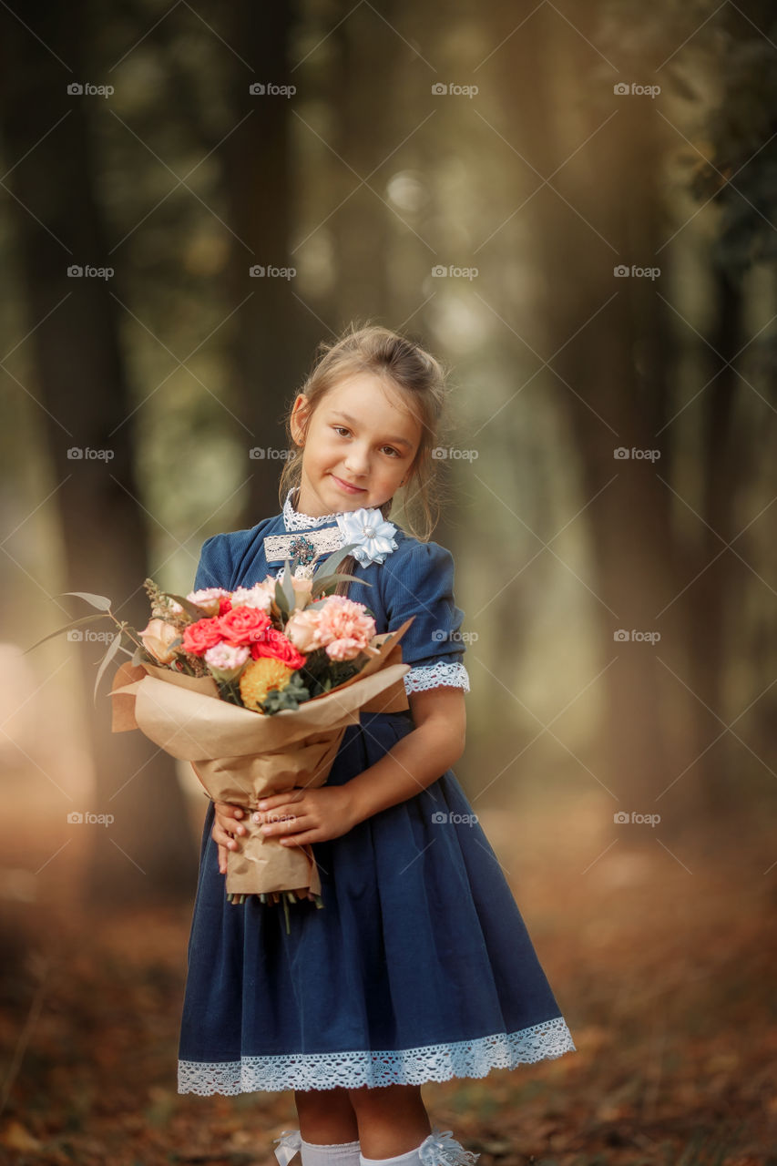 Little schoolgirl with a bouquet at a park 