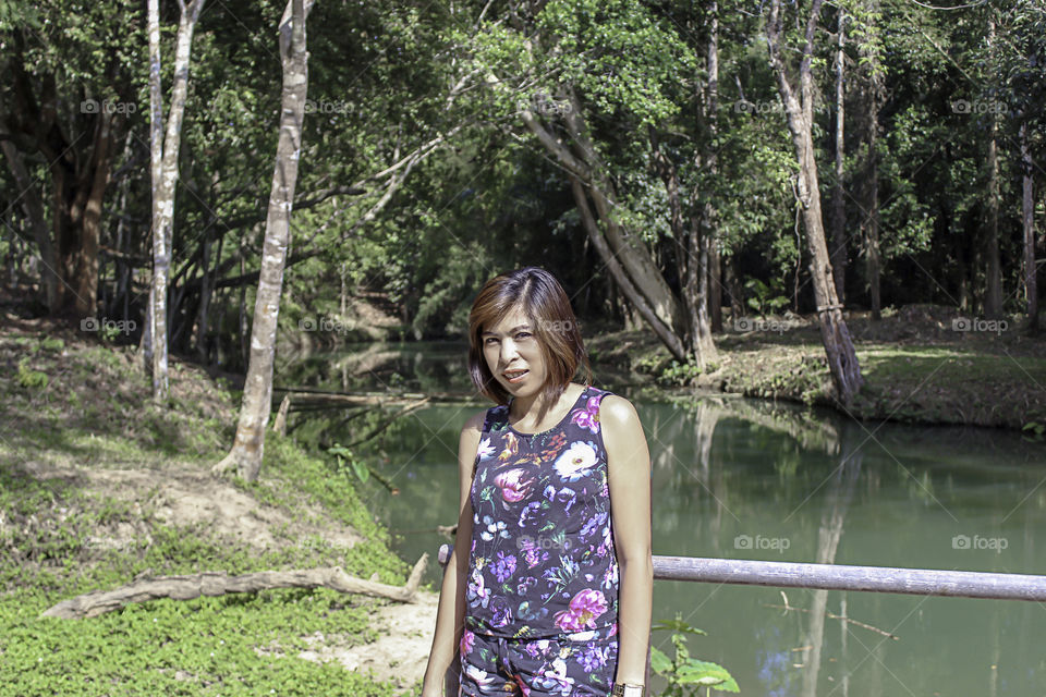 Asean woman and water in the stream is green and bright green tree at Kapo Waterfall Fores Park , Chumphon in Thailand.