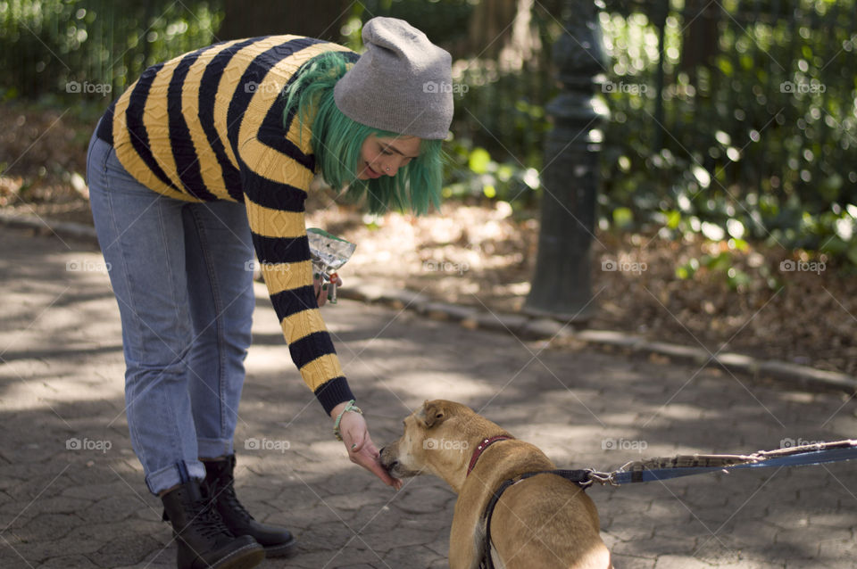 Alternative girl with green hair feeding a dog