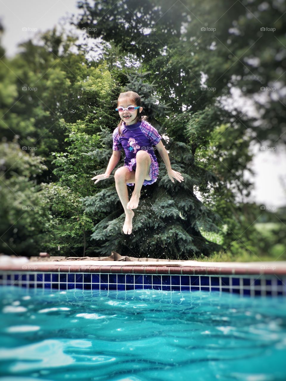 Cute girl jumping in swimming pool