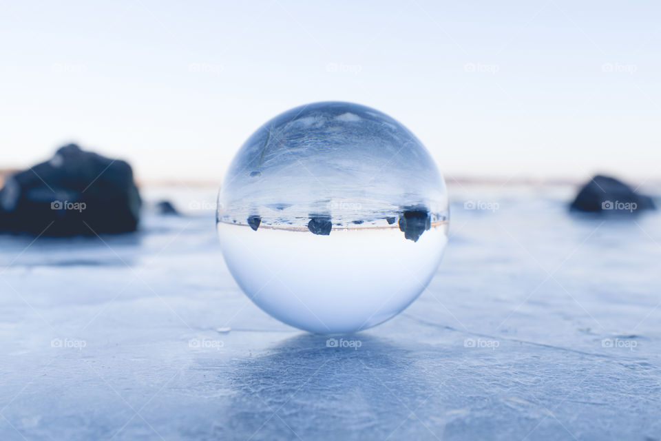 Glass orb on ice surface with rocks