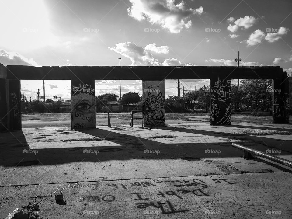 Shadows in black and white at sunset at an abandoned outdoor urban art facility.  The debt I owe is something worth living 4 graffiti  painted on floor.