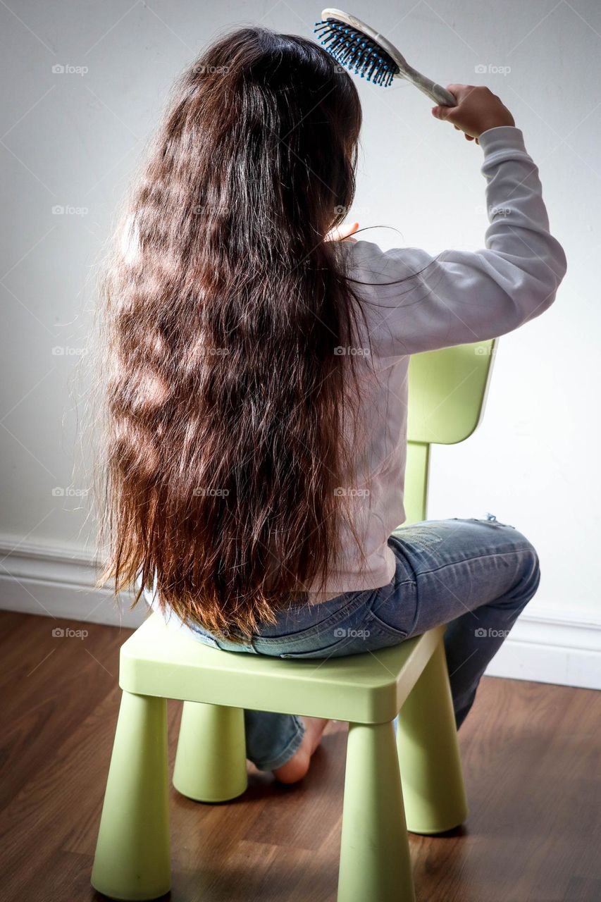 Girl with a gorgeous long hair is sitting on a chair