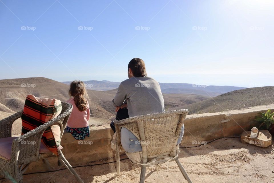 Father and daughter sitting stare the view of the desert 