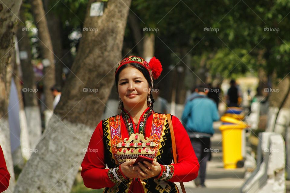 a woman in a national dress smiling at the camera walking around the city