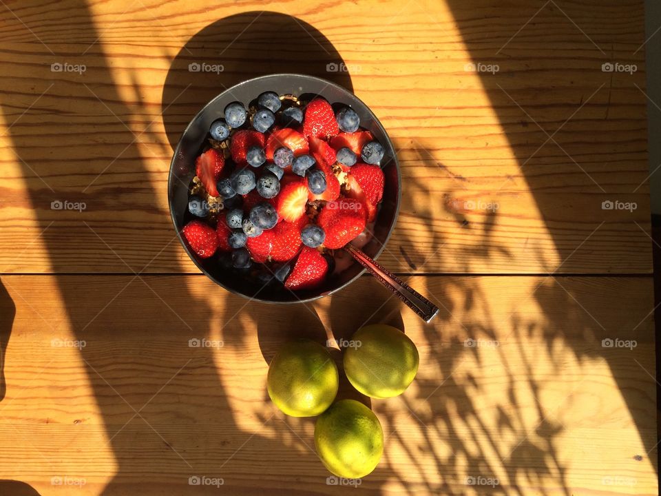Fresh berries in a bowl with a side of three limes